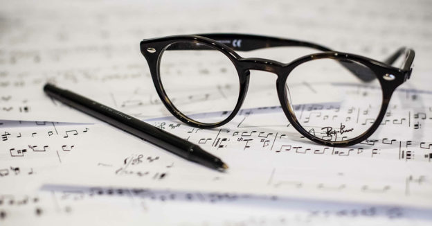 Glasses and pen sitting on top of sheet music